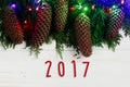 2017 sign text on christmas garland lights and pine cones on fir Royalty Free Stock Photo