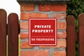 Sign with text Private Property No Trespassing on brick column of wooden fence Royalty Free Stock Photo