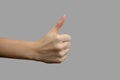 The sign of the thumb. Hand with white skin, showing the like sign, on a gray isolated background. Close-up, selective focus