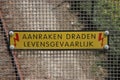 Sign at a viaduct in dutch `aanraken dragen levensgevaarlijk` which means touching wires is dangerous above railroad track.