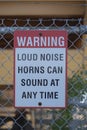 Sign warning loud noise horns can sound at any time on the fence at port. Royalty Free Stock Photo