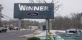 Sign for the Winner Ford car dealership near the road on a snowy day