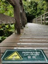 Sign on the wooden bridge showing warning of caution wet floor. Royalty Free Stock Photo