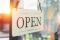 Sign wooden open hanging on front glass door of cafe.