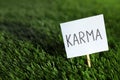Sign with word Karma on green grass, closeup. Space for text