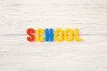 The sign, word school on a white wooden background, top view. Kids colored plastic letters