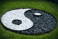 Sign of yin yang laid out of black and white stones on a green lawn Royalty Free Stock Photo