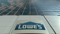 Signage board with Lowe`s logo. Modern office building facade. Editorial 3D rendering