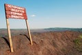 Signboard with an inscription in Russian - Be careful! Mining operations are ongoing - installed on the edge of a mining quarry