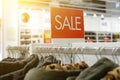 Signboard with inscription sale in fashion store. Sale, discounts. hangers with clothes during sale. Black Friday. Shallow depth