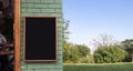 Signboard mockup empty black frame for logo and text on the wood wall and blur garden background