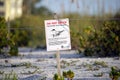 Signboard with warning about nesting area of sea birds on seaside beach with small sand dunes and grassy vegetation on