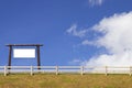 Signboard and wood fence with grass and blue sky Royalty Free Stock Photo