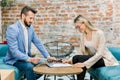 Signing the business contract. Two young Caucasian business people, man and woman, sitting at the table in the office Royalty Free Stock Photo