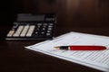 Signing a contract, pen and calculator on a wooden table Royalty Free Stock Photo