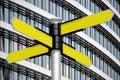 Yellow signpost with four arrows, office building in background Royalty Free Stock Photo
