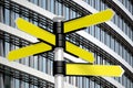 Yellow signpost with five arrows, office building in background Royalty Free Stock Photo