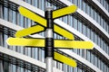 Yellow signpost with seven arrows, office building in background
