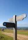 A signpost and a couple walking with a dog on the South Downs Way near Brighton in Sussex, England, UK Royalty Free Stock Photo