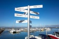 Signpost of direction and distance of landmarks in and around Melbourne at Wyndham Harbour with yacht berths in the background.
