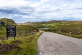 Signpost leading the way to the Old School Restaurant in a picturesque mountain landscape in Drumbeg