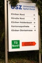 Signpost of University Zurich Hospital showing directions in German and an orange arrow