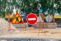 signs entry is prohibited and roadworks are underway behind which there is pile of rubble and protective concrete blocks