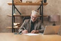 Signs a purchase agreement. Elderly man smiling at the table, paper work in the office Royalty Free Stock Photo