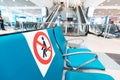 Signs on the seats at the airport draw line between safe and dangerous areas for Seating to comply with safe social distance. Royalty Free Stock Photo