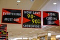 Signs for a store wide 90% off bankruptcy sale hanging from the ceiling of a store.