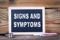 Signs and symptoms. Chalkboard on a wooden background Royalty Free Stock Photo