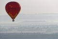 An hot air balloon flies over the morning mists