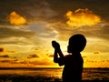Sihlouette of praying kid during sunset Royalty Free Stock Photo