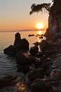 Sihouette of a young couple sitting on a rock at sunset, Kastani Mamma Mia beach, island of Skopelos