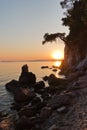 Sihouette of a young couple sitting on a rock at sunset, Kastani Mamma Mia beach, island of Skopelos