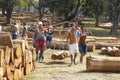 People lift wood logs by manually using ropes and logs as carriers