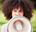 Silence becomes cowardice. a young woman screaming into a loudspeaker while protesting in the park.