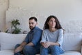 Silent couple sit on sofa staring aside after fight