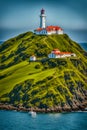 Silent Keeper of the Sea Lighthouse on Grassy Hill Royalty Free Stock Photo