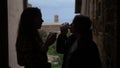 A silhoettes of two young women stand on the balcony - drinks coffee and talking
