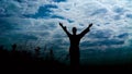 Silhouete of man stands on the stone rock with raised arms in windy day. Slowly