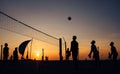 Silhouets of men playing beach volleyball at the evening glory time