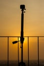 Silhouette of a action camera mounted on a tripod for taking a time lapse of a sunset or sunrise from a tall apartments balcony. Royalty Free Stock Photo