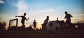 Silhouette action sport outdoors of kids having fun playing soccer football for exercise in community rural area under the twiligh