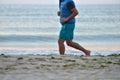 Silhouette of active adult man running and exercising on the beach early in the morning, at the sunrise. Calm water. Healthy life