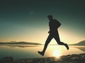 Silhouette of active athlete runner running on sunrise shore. Morning healthy lifestyle exercise