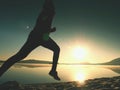 Silhouette of active athlete runner running on sunrise shore. Morning healthy lifestyle exercise