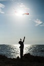 Silhouette of active free little child holding flying kite and looking up on sea coast on summer sunset holiday Royalty Free Stock Photo