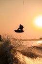 silhouette of active man making trick with wakeboard on bright orange sky and sun background. Royalty Free Stock Photo