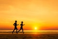 Silhouette of active sporty couple running on the beach, sunset Royalty Free Stock Photo